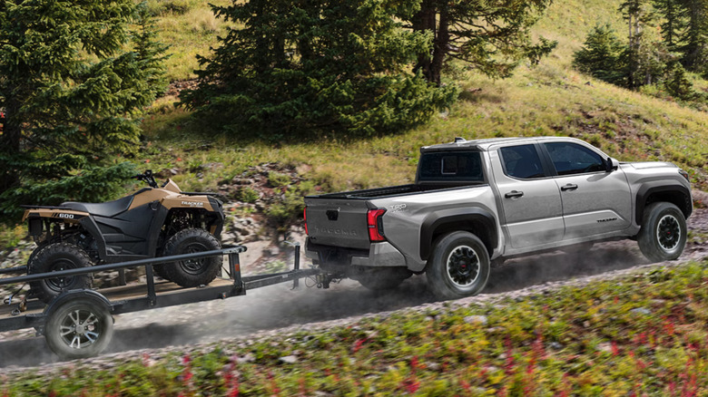 silver 2026 Toyota Tacoma towing a ATV uphill