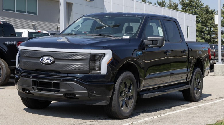 Black Ford F-150 Lightning in front of Ford dealership