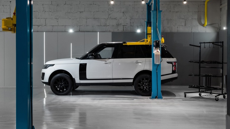 White Range Rover parked inside a service garage next to a vehicle lift