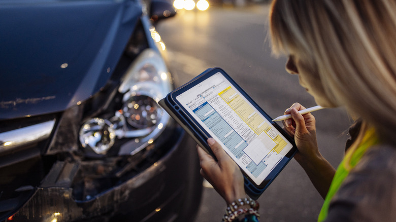 Woman inspecting damage on an automobile