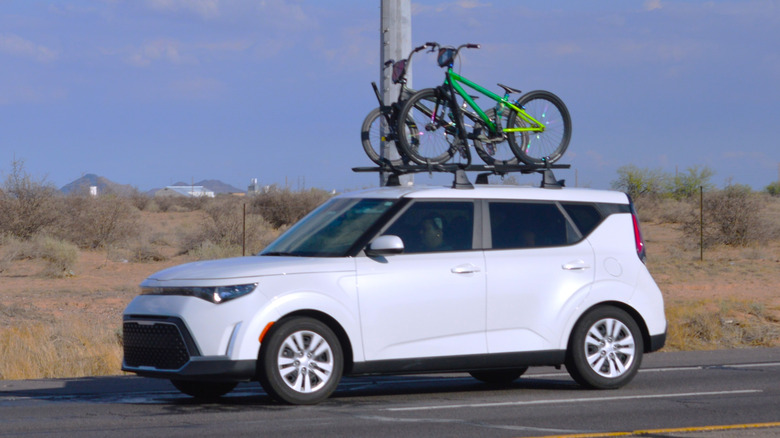 A white Kia Soul with a bicycle rack.