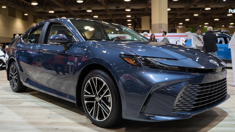 Blue Toyota Camry sedan displayed on a showroom floor at an auto show