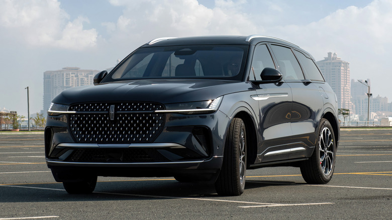 A dark-colored Lincoln Nautilus SUV parked on pavement with buildings in the background.
