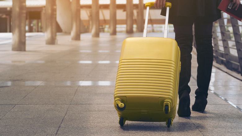 A young female traveler rolling a suitcase as she walks through an airport