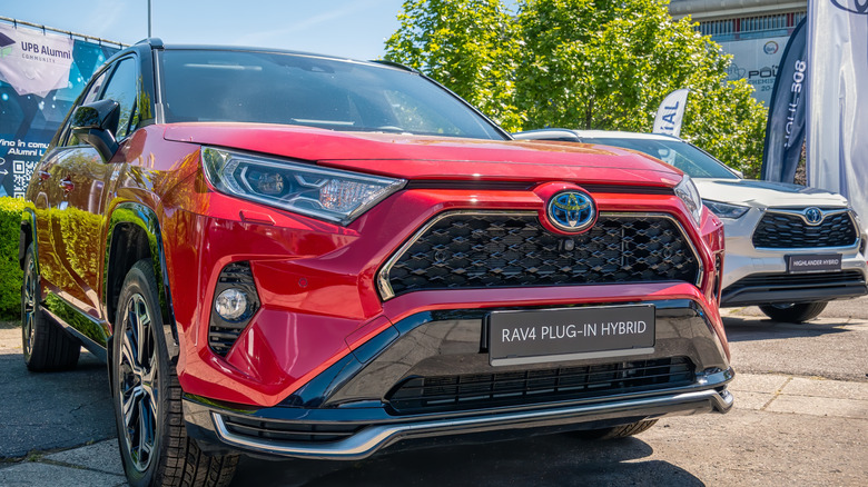 A red 2025 Toyota RAV4 plug-in hybrid in a parking lot.