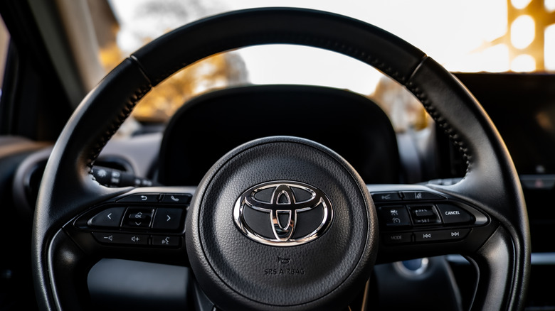 Close-up of a steering wheel with the Toyota logo in the center.