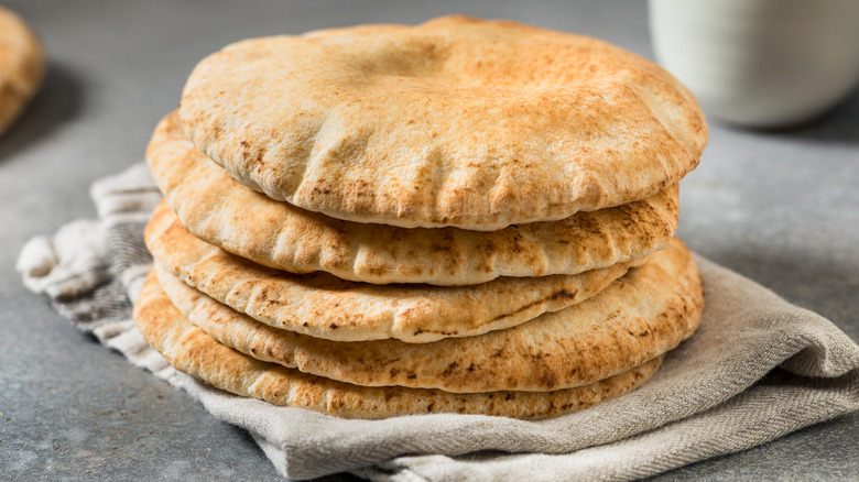 Stack of homemade pita bread on a tan towel.