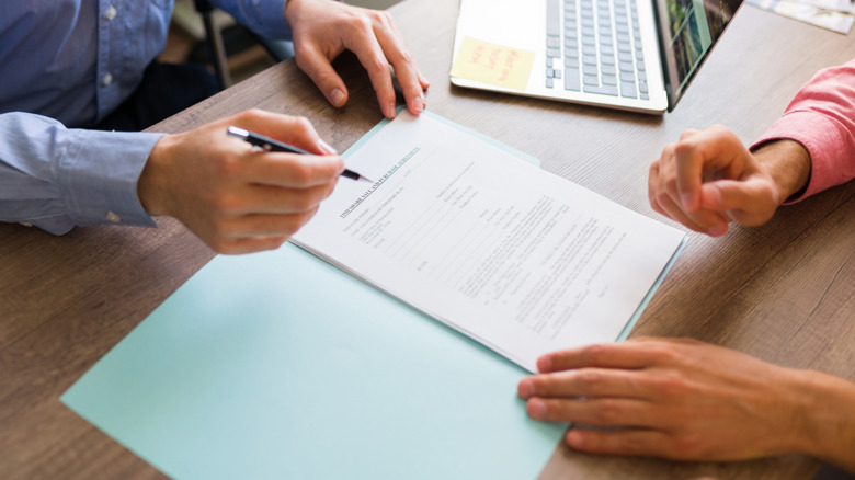 A person at a desk preparing to sign a document