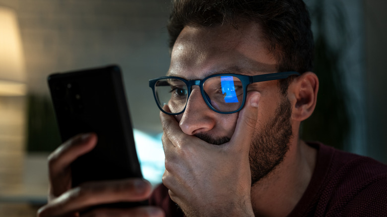 A man looking at his phone with a concerned expression