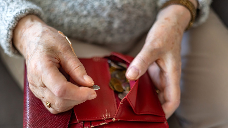 Close-up of an elderly woman's hands holding a wallet with coins.