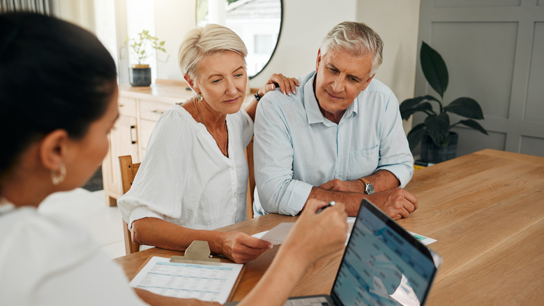 a mature couple talking to an accountant at home.