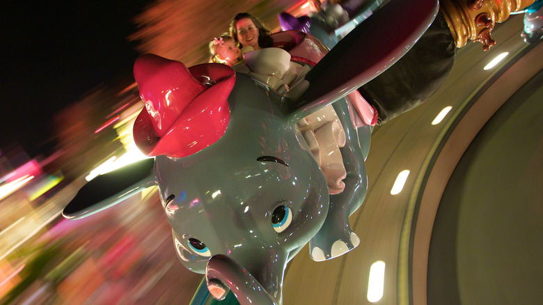 Two people riding Dumbo ride at night