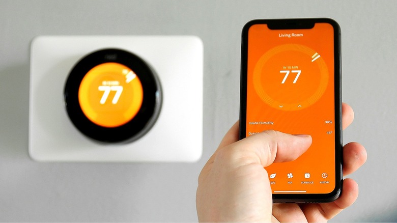 Person adjusting thermostat with phone