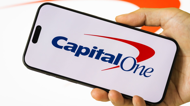 In this photo illustration, a person holds a smartphone displaying the logo of Capital One Financial Corporation