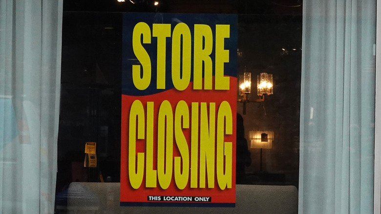 A sign on a window with the words "Store Closing" in bold yellow.