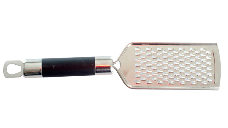 A flat metal cheese greater with a cylindrical handle