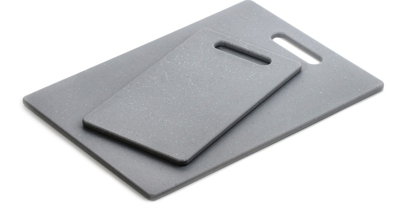 Two grey flat cutting boards, with the smaller one laying on the bigger one
