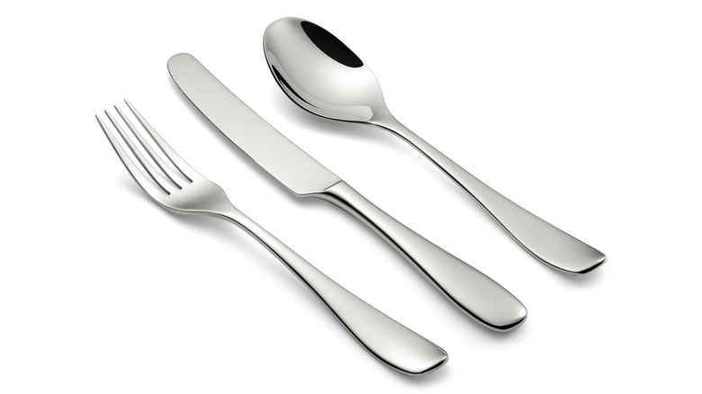 a fork, butter knife, and spoon laying on a white blank surface