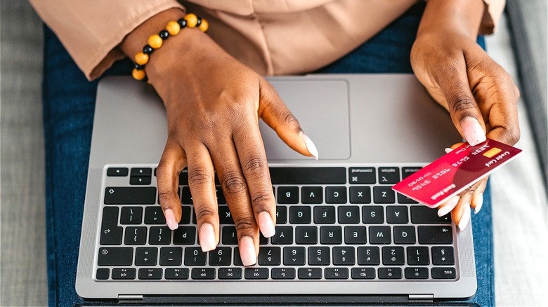 Person typing, holding credit card