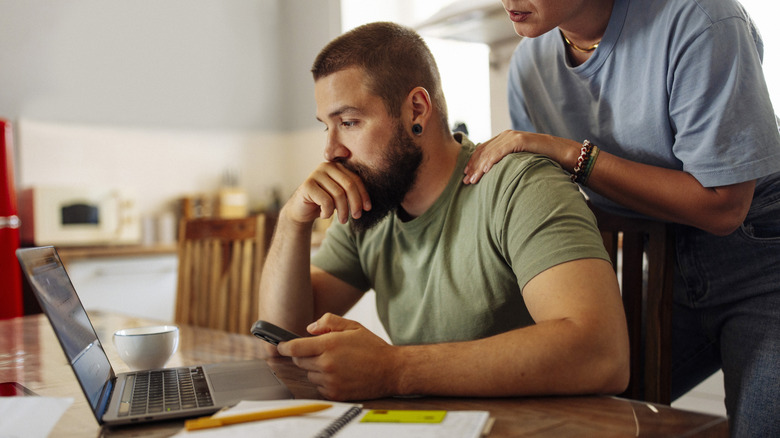 Couple looking at computer screen with stressed look.
