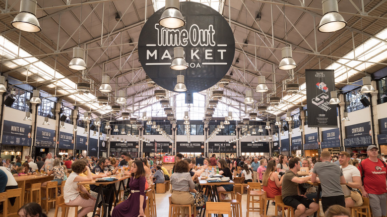 Tourists sitting in crowded food hall Time Out Market Lisboa.