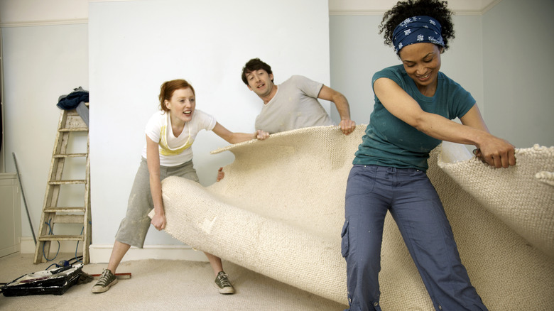 friends pulling up old carpet