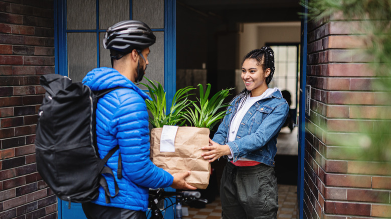 Delivery person giving paper bag to customer.