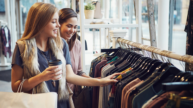 Women laughing at a retail store while going through a clothing aisle