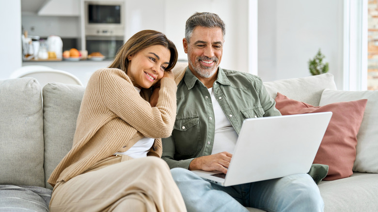 Mature man and woman looking at computer watching video