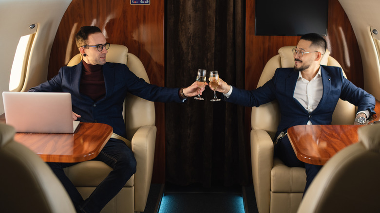 Two Sucess Mid-adult Businessman couple sitting inside a private jet airplane