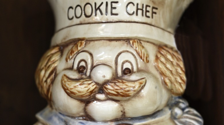 Close up of a vintage cookie jar in the shape of a cartoon chef wearing a hat that says cookie chef.