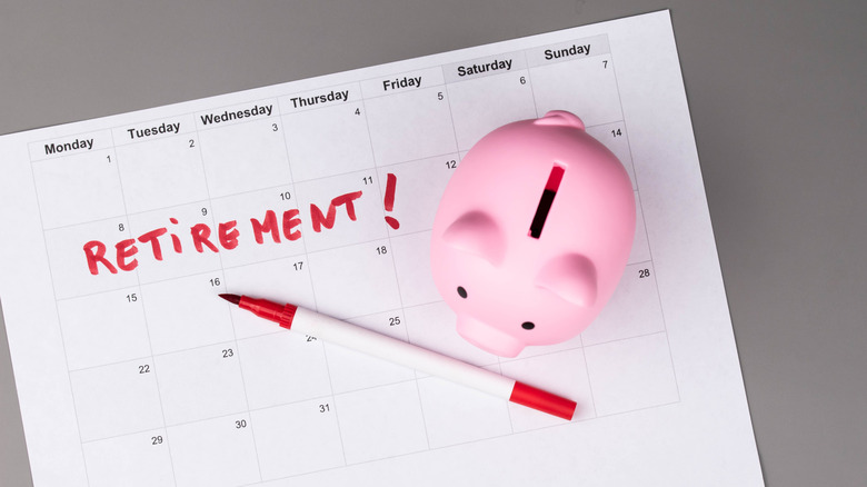 A calendar with the word retirement written on it under a pen and piggie bank