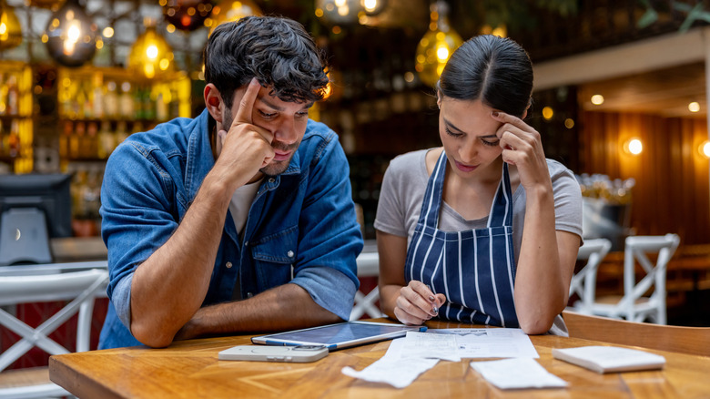 Restaurant owners at table checking their debt