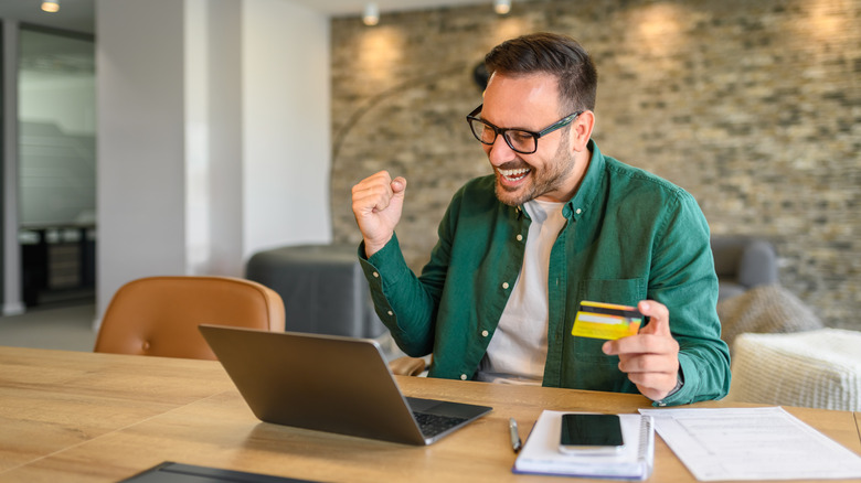 Man happy after using credit card to check out on his computer