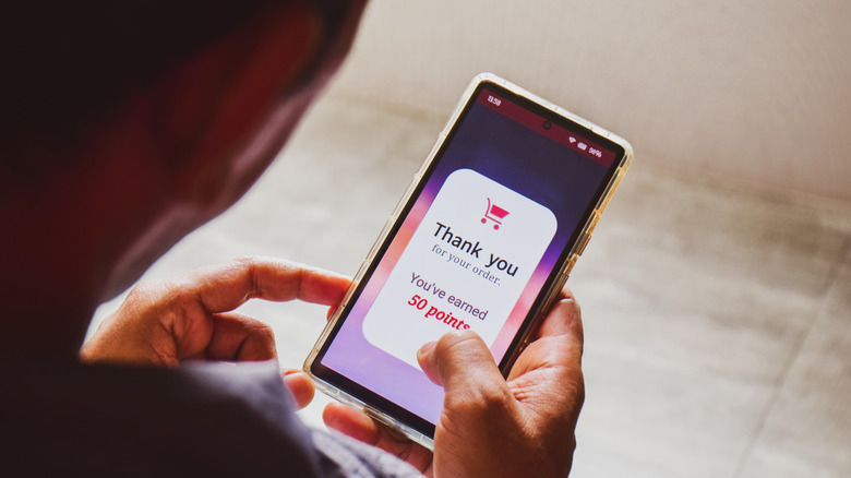 Man holding phone showing he earned 50 loyalty points