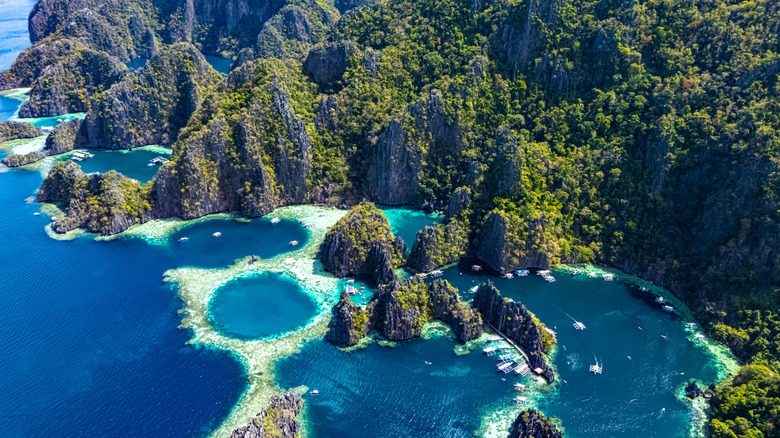 Aerial view of blue ocean waters next to a mountainous coastline covered with dense vegetation
