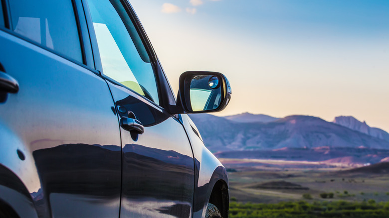 An SUV driving through a scenic wilderness landscape at sunrise