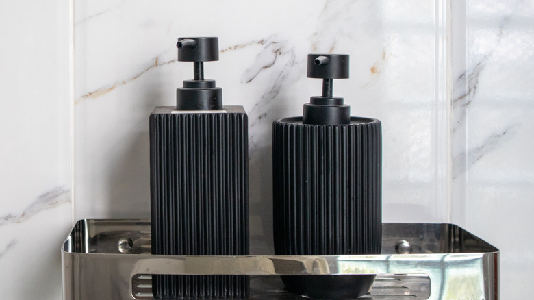 Two black bottles on a small shelf in a shower