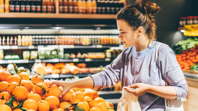 A women picking oranges at grocery store.