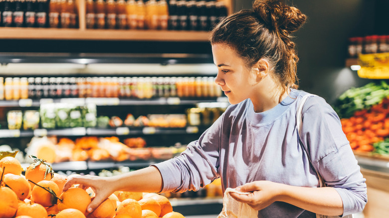 A women picking oranges at grocery store.