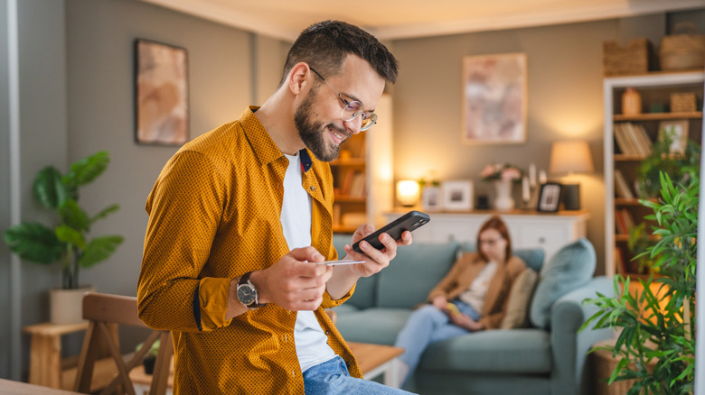 A young man using a credit card to make a purchase on his phone