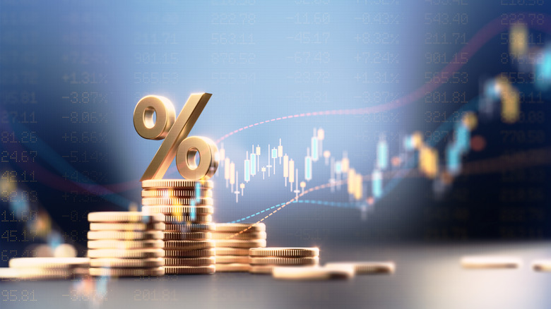 Digitized gold percentage symbol placed atop a stack of gold coins