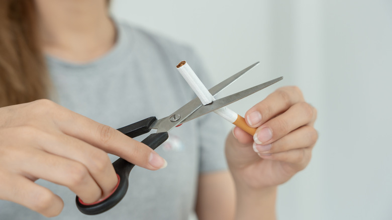A woman cutting a cigarette with scissors