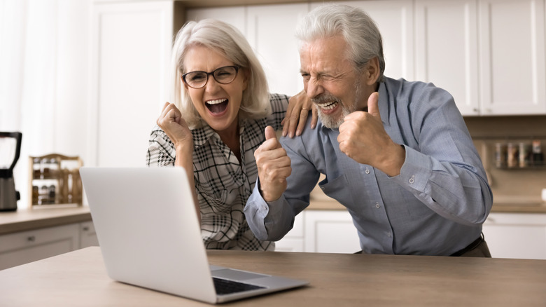 Happy senior citizens viewing a laptop computer screen