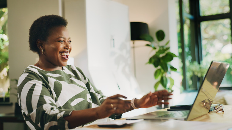 An ecstatic Gen X woman smiling about good news discovered on her laptop.