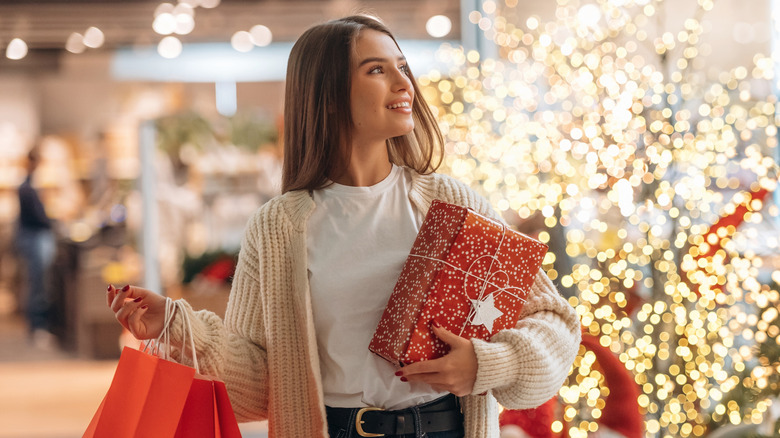 Young woman holiday shopping in a store lined with Christmas trees
