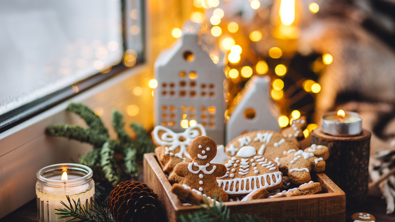 Festive frosted gingerbread cookies, pine spray, candles, and twinkling lights in a window space