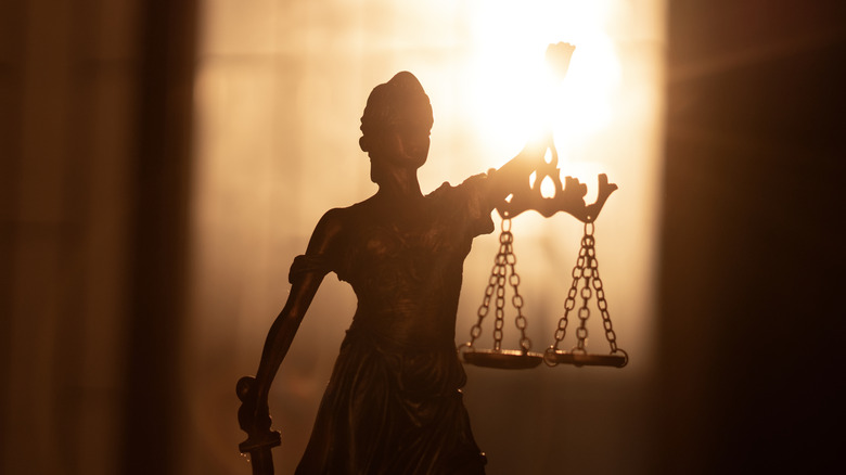 A dramatic backlit photo of a statue of Lady Justice
