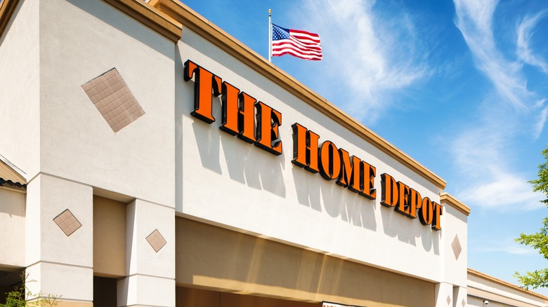 Exterior of a Home Depot store with the orange Home Depot sign and an American flag flying above the building