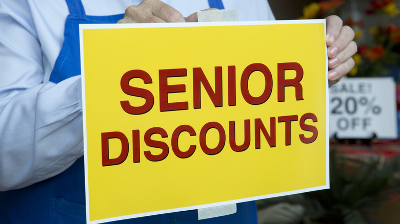 A worker taping a senior discount sign in a store window